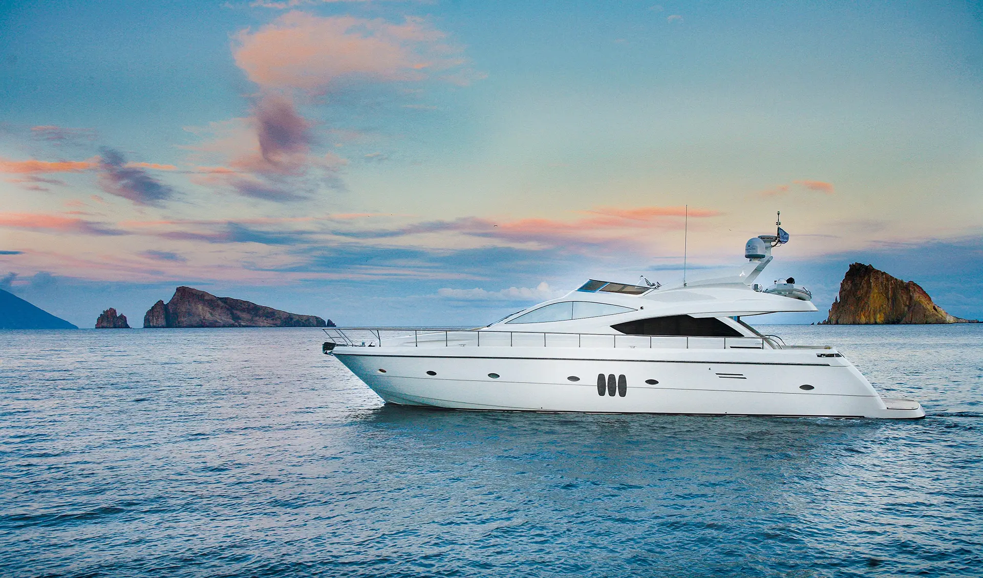 luxury yacht on calm water with large rock islands in the distance after yacht management services based in West Palm Beach, FL